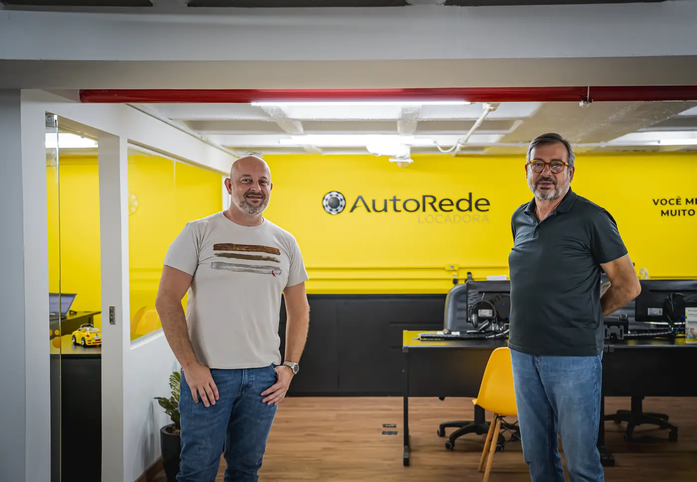 Equipe da AutoRede Locadora na recepção do Estoril, com a parede amarela da marca
